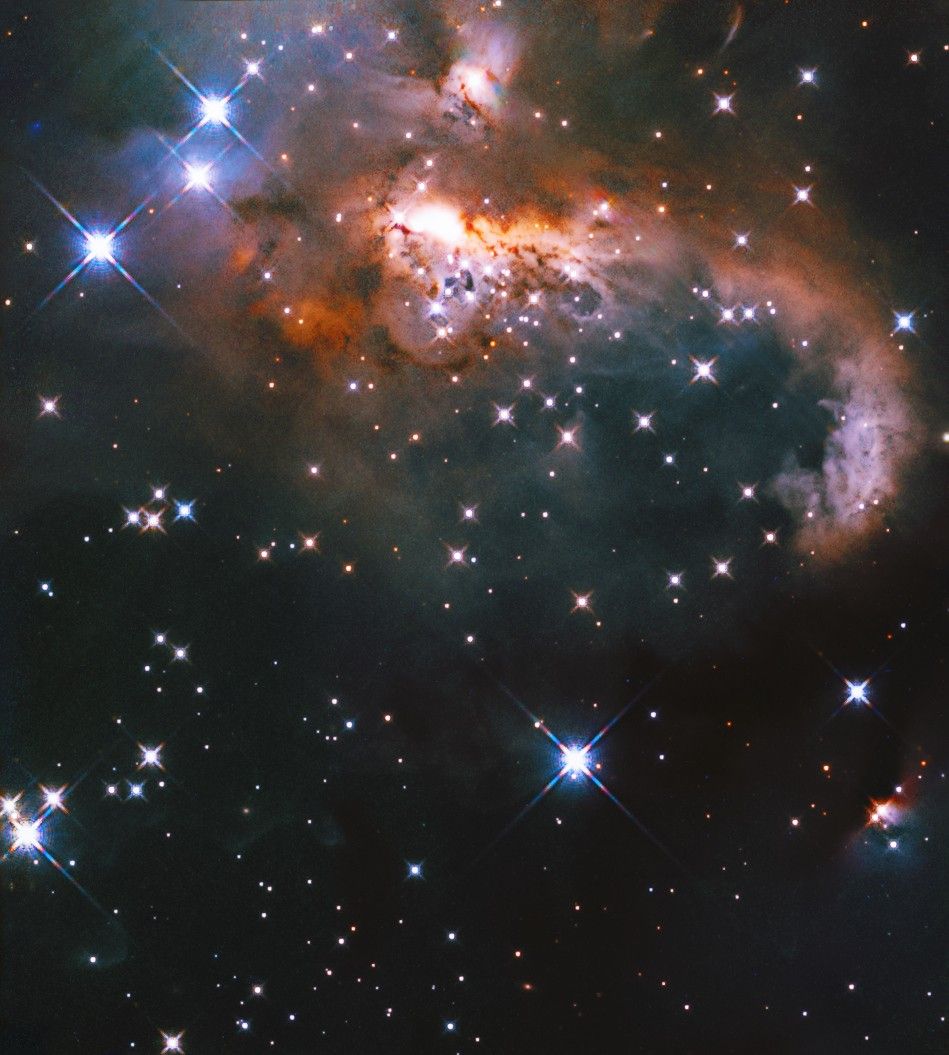 Bluish, brownish, orange-red nebula in upper half of image. Image is dotted with blue-white  and reddish stars throughout.